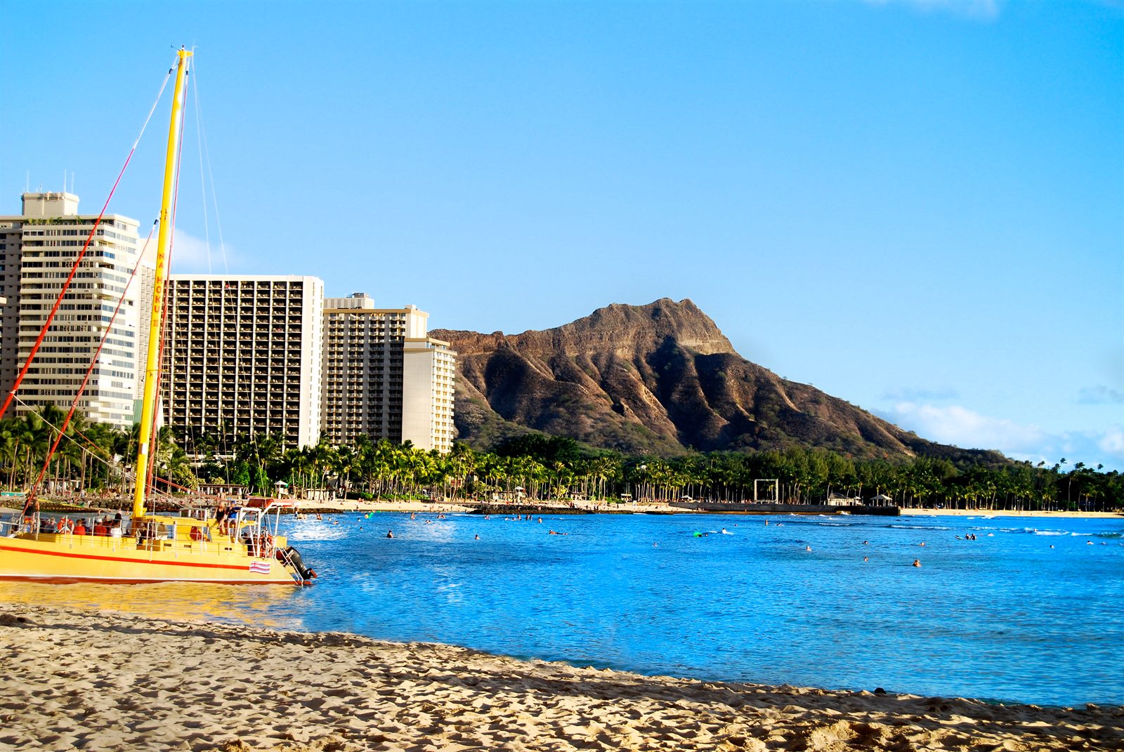 Catamaran pulled up on Waikiki Beach with hotels and Diamond Head behind