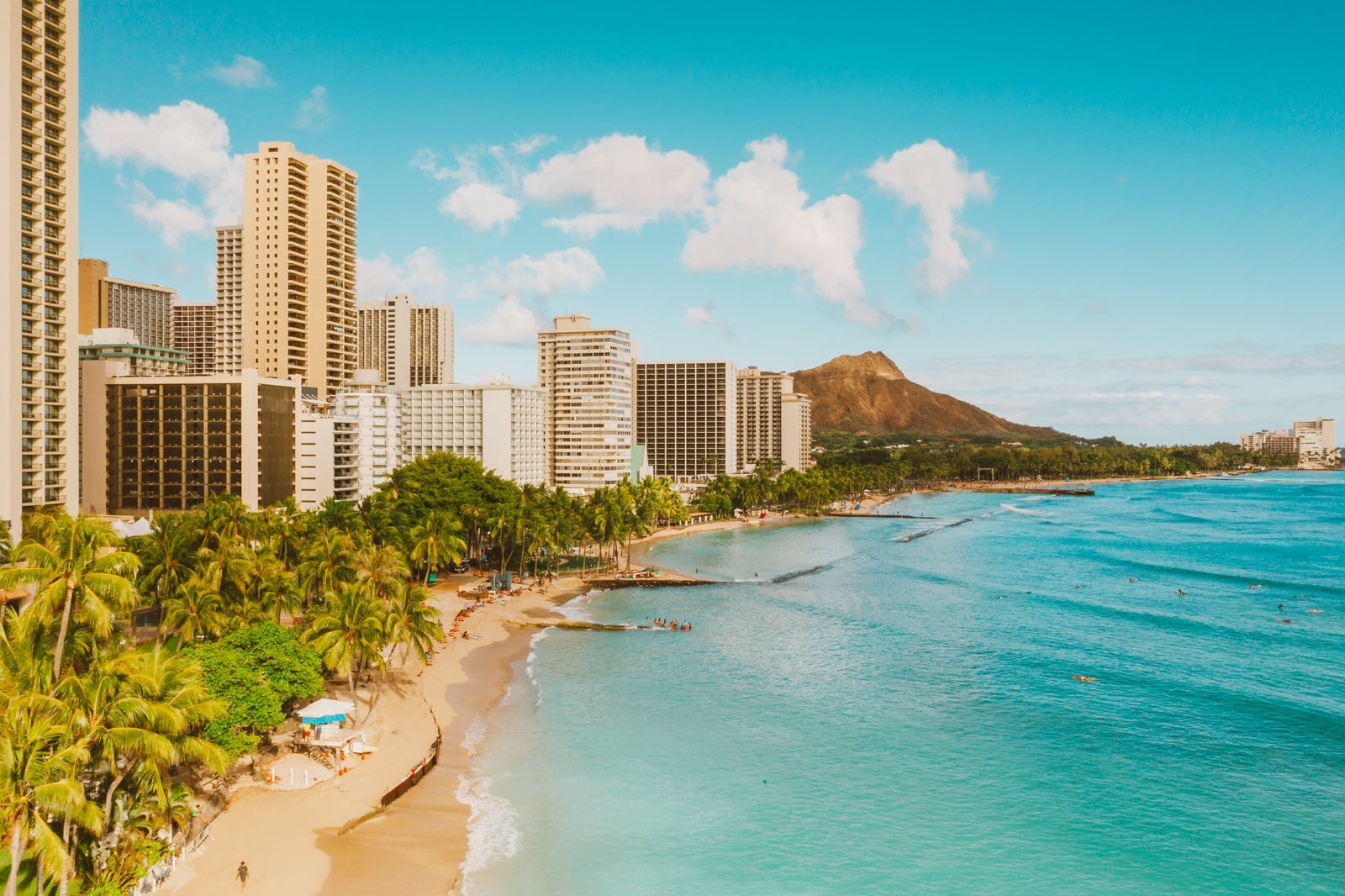 Hotels lining the sand at Waikiki Beach with Diamond Head in the distance