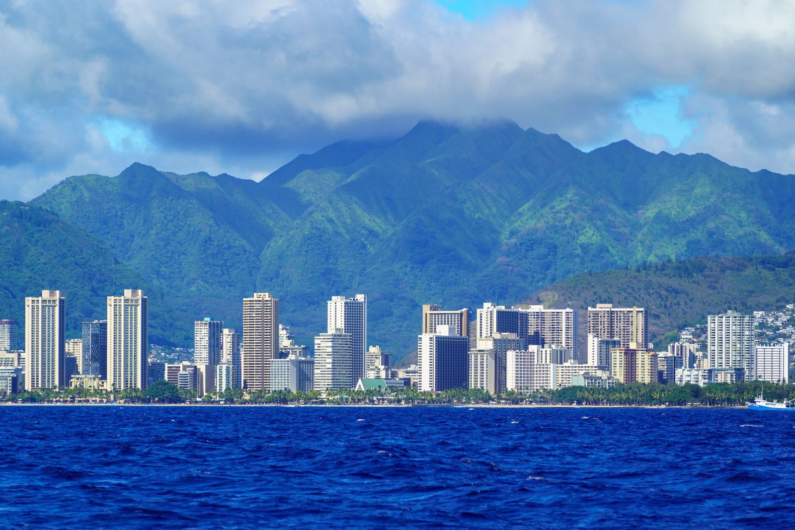 Downtown Honolulu towers along the waterfront beneath green mountains, the setting of the Honolulu cruise terminal